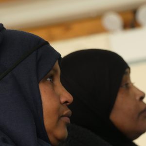 Two Somali women sit watching the presentation